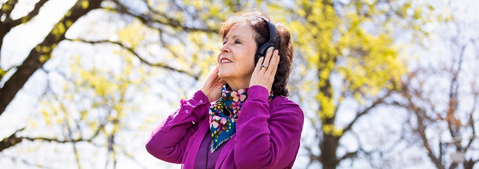 Bobbin Beam Voice Artist listening via headphones in the light with trees in the background